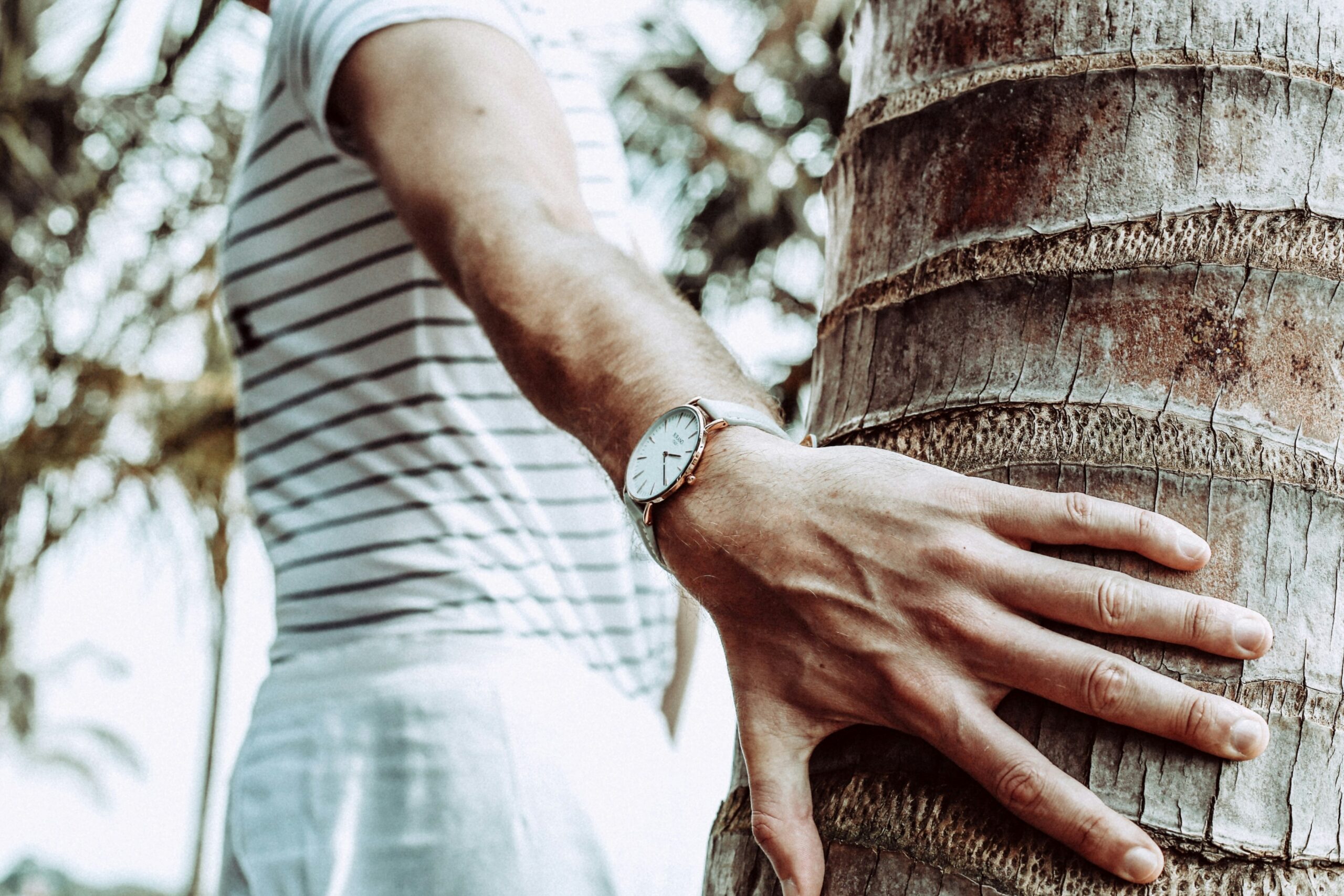 Hand holding a modern sustainable watch under sunlight, showcasing its sleek design