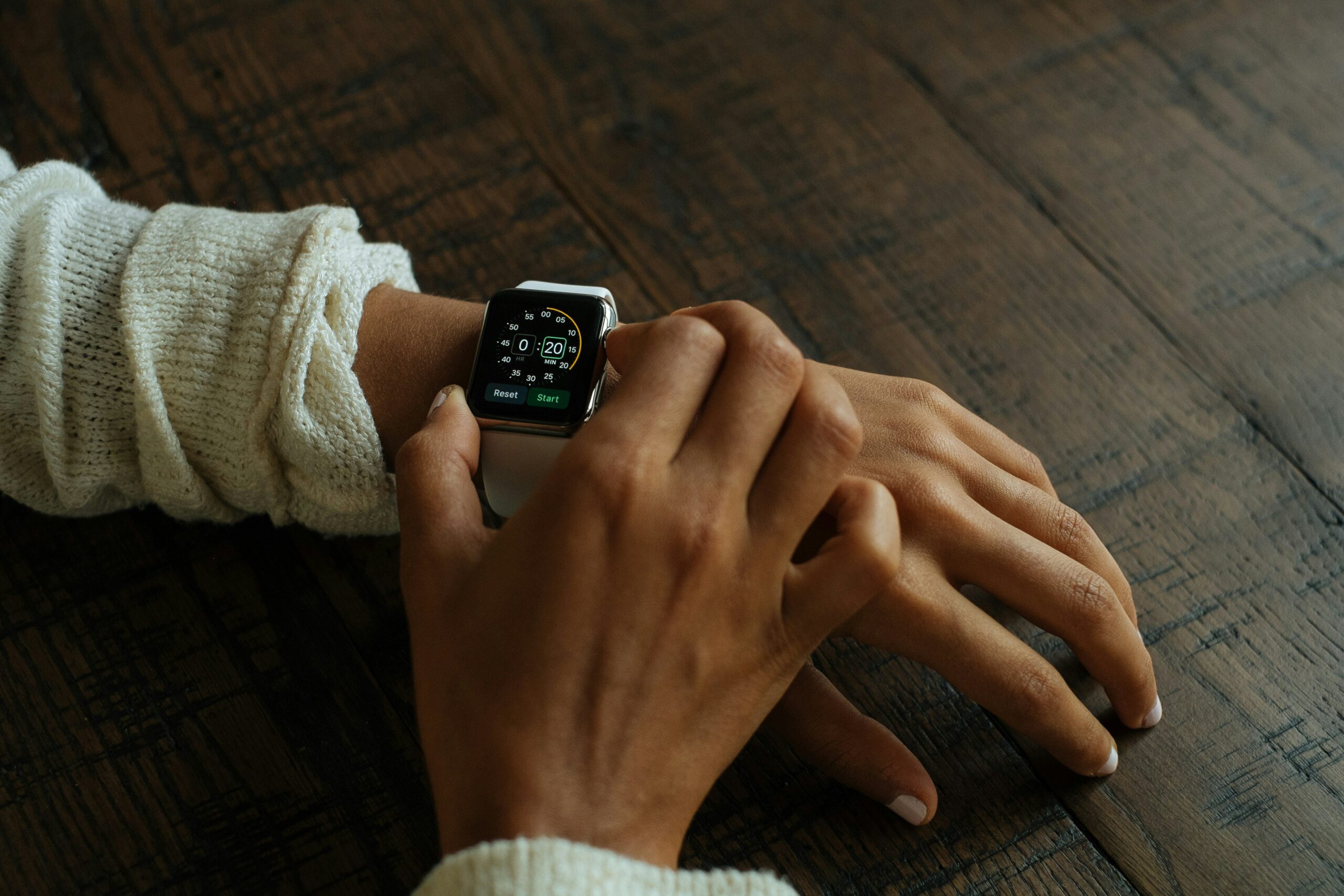 A closeup shot of a petite smartwatch styled alongside delicate bracelets and rings.