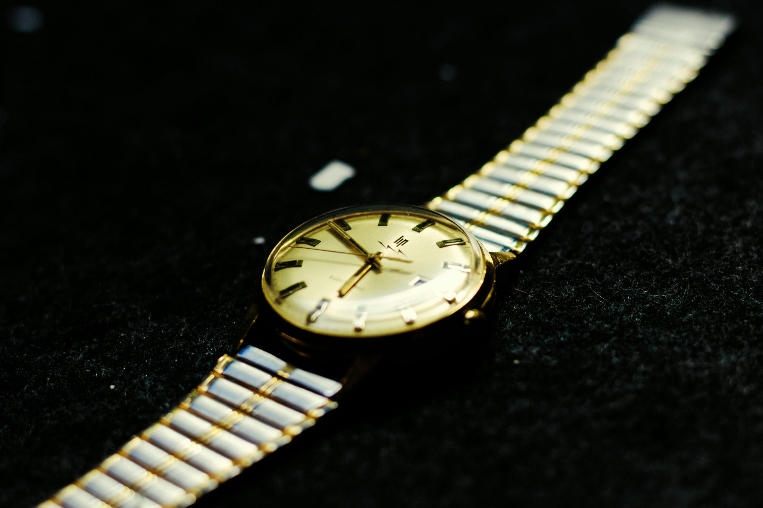 Photo of Timex Q Reissue laying on wooden table against rustic backdrop showcasing its domed crystal face and vibrant blue dial.