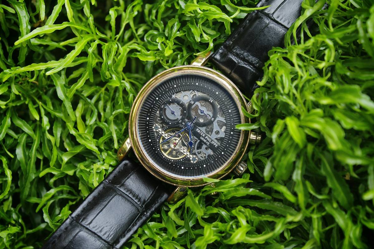 A lifestyle photo of someone wearing a Fossil Gen 6 Smartwatch with a vibrant copper metallic finish while typing on a laptop outdoors.