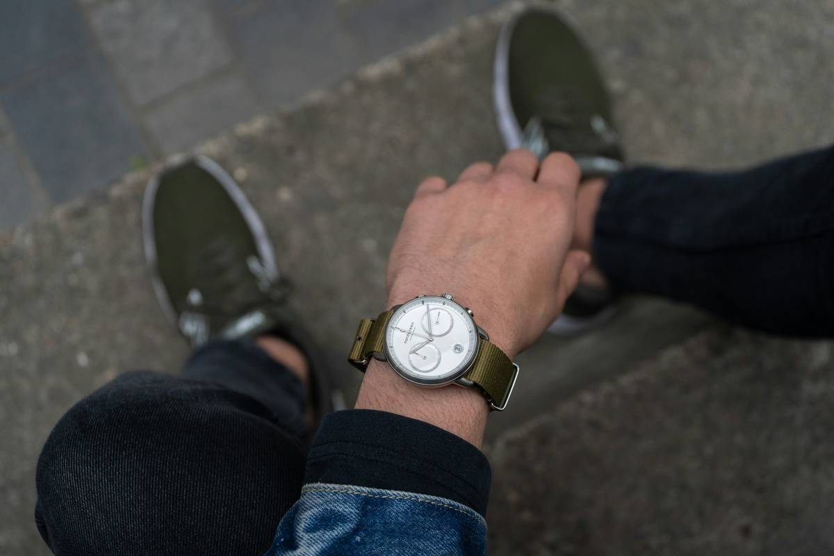 A side-by-side comparison of a silicon strap watch and a leather strap watch on a wooden table.