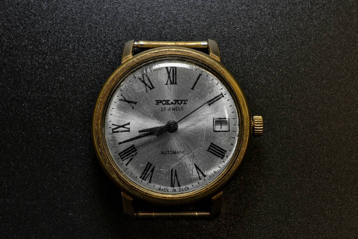 A stylish woman wearing a silver mineral glass fashion watch against a black dress background.